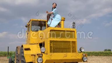 有魅力的女孩在蓝色的背景下，在黄色的农业<strong>机器</strong>上<strong>缓慢</strong>地跳舞